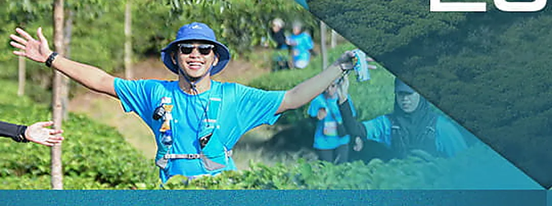 Pelari IFTR berjersey biru merentangkan tangan di tengah kebun teh Puncak Bogor