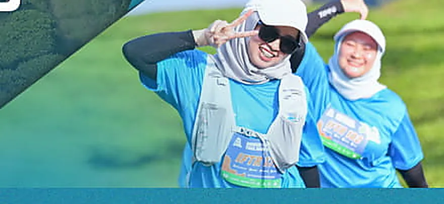 Dua pelari IFTR berjersey biru dengan hydration vest berpose di jalur kebun teh